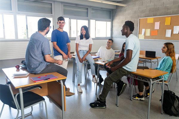 Image of a group of teenagers and a teacher talking in a classroom